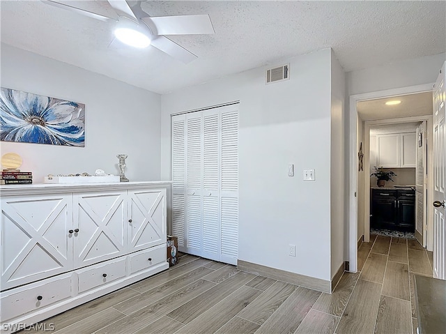 bedroom featuring a closet, ceiling fan, light hardwood / wood-style flooring, and a textured ceiling