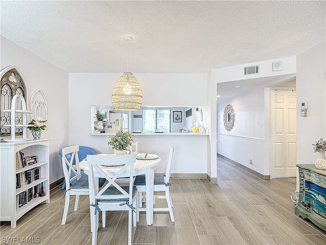 dining space with a textured ceiling and hardwood / wood-style flooring