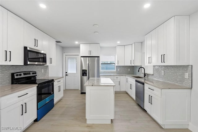 kitchen featuring light stone countertops, sink, stainless steel appliances, a kitchen island, and white cabinets