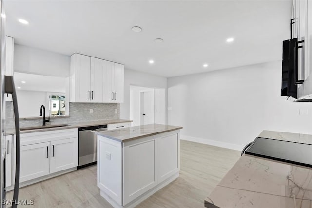 kitchen with white cabinetry, dishwasher, light stone countertops, sink, and a kitchen island