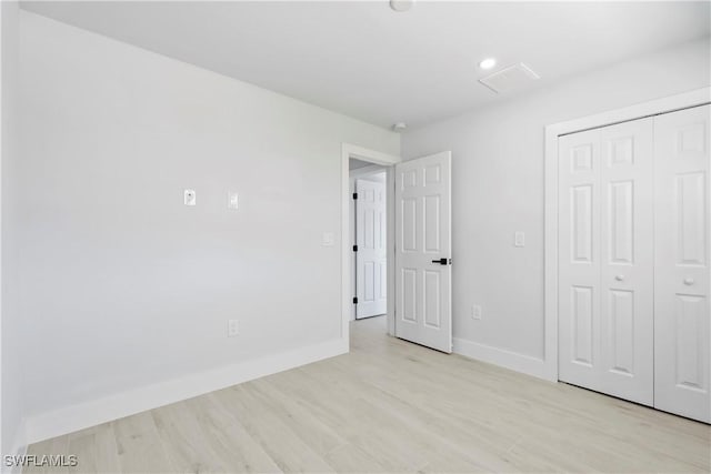 unfurnished bedroom with a closet and light hardwood / wood-style flooring