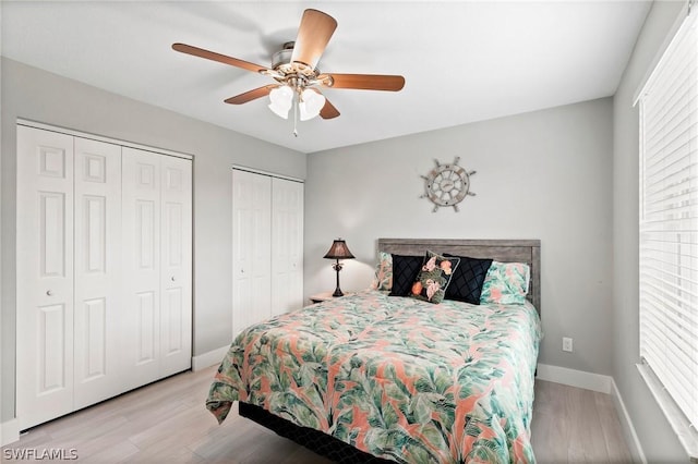 bedroom featuring multiple windows, two closets, ceiling fan, and light hardwood / wood-style flooring