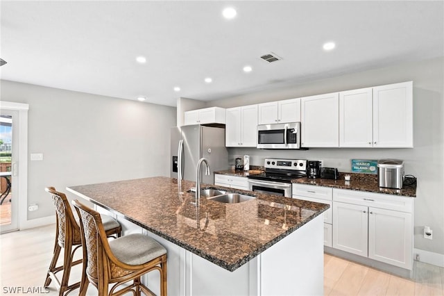 kitchen with appliances with stainless steel finishes, sink, a center island with sink, and white cabinets