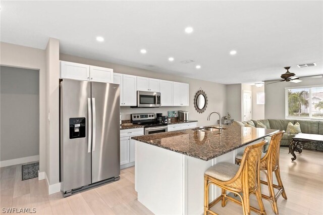 kitchen featuring white cabinetry, sink, stainless steel appliances, and an island with sink