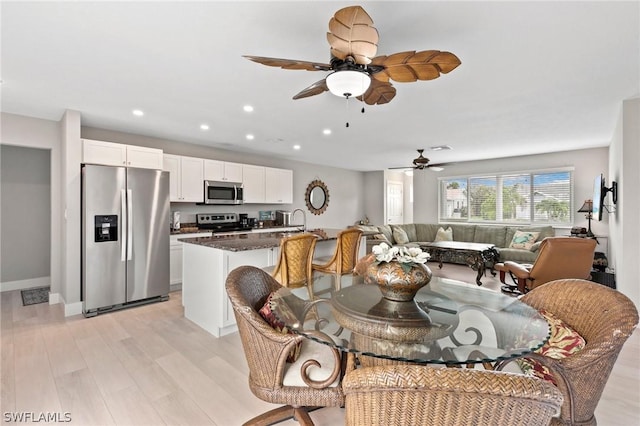 dining room with ceiling fan, sink, and light hardwood / wood-style floors