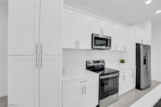 kitchen with appliances with stainless steel finishes, light hardwood / wood-style floors, and white cabinets