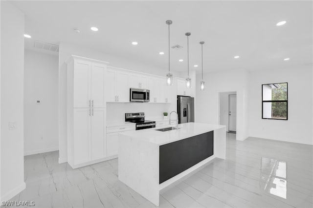 kitchen featuring a kitchen island with sink, sink, white cabinets, appliances with stainless steel finishes, and decorative light fixtures