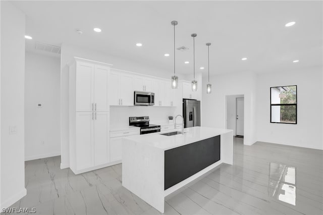 kitchen featuring appliances with stainless steel finishes, a center island with sink, pendant lighting, and white cabinets