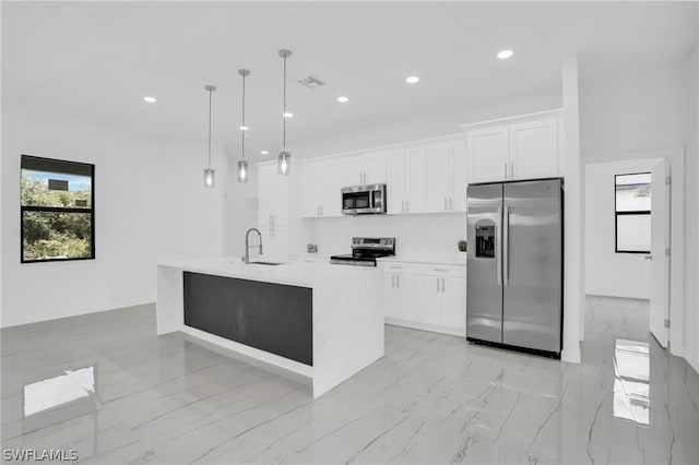 kitchen featuring white cabinets, sink, decorative light fixtures, a kitchen island with sink, and appliances with stainless steel finishes