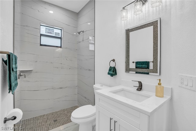 bathroom with vanity, toilet, and tiled shower