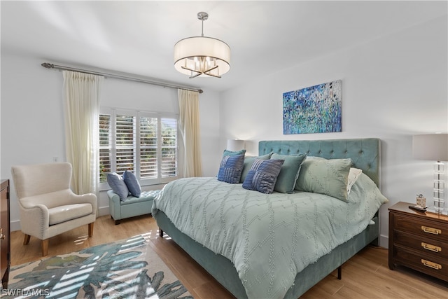 bedroom with light wood-type flooring and an inviting chandelier