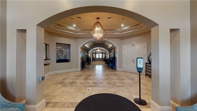 entryway featuring a tray ceiling, an inviting chandelier, and crown molding