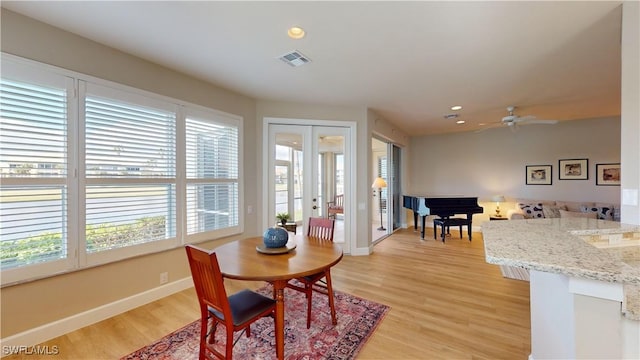 dining room with plenty of natural light, ceiling fan, light wood-type flooring, and french doors