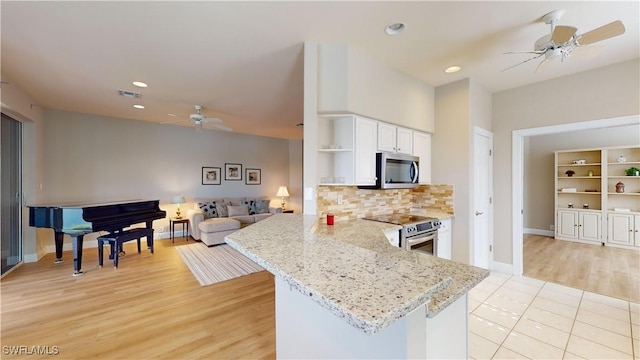 kitchen featuring kitchen peninsula, appliances with stainless steel finishes, light stone counters, light hardwood / wood-style floors, and white cabinetry