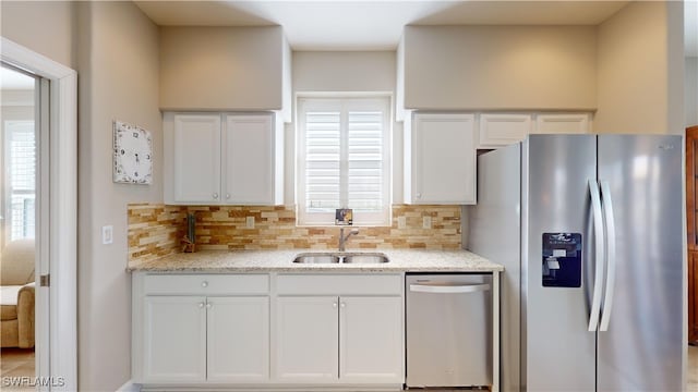 kitchen featuring backsplash, white cabinets, sink, light stone counters, and stainless steel appliances