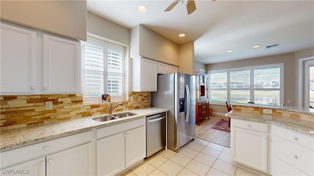 kitchen with white cabinetry, sink, stainless steel appliances, and light stone counters