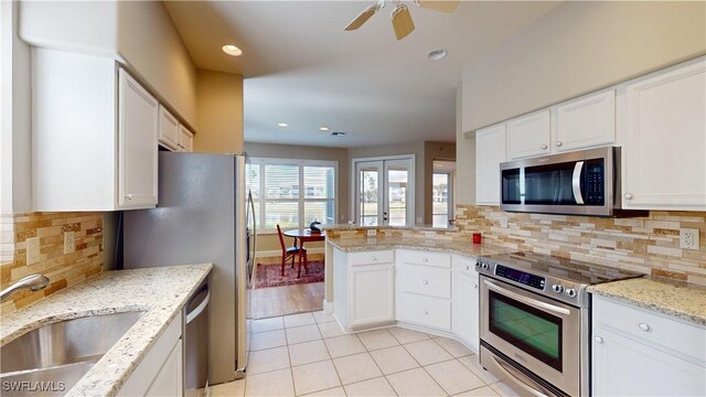 kitchen with decorative backsplash, stainless steel appliances, white cabinetry, and sink