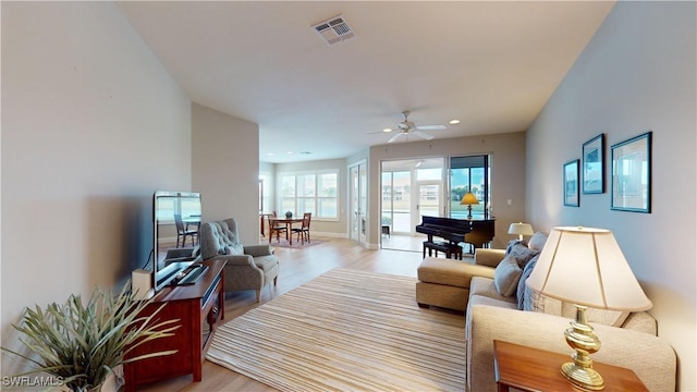 living room with light hardwood / wood-style flooring and ceiling fan