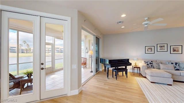 interior space with plenty of natural light, a water view, french doors, and light wood-type flooring