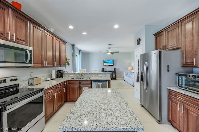 kitchen featuring a center island, appliances with stainless steel finishes, ceiling fan, and sink