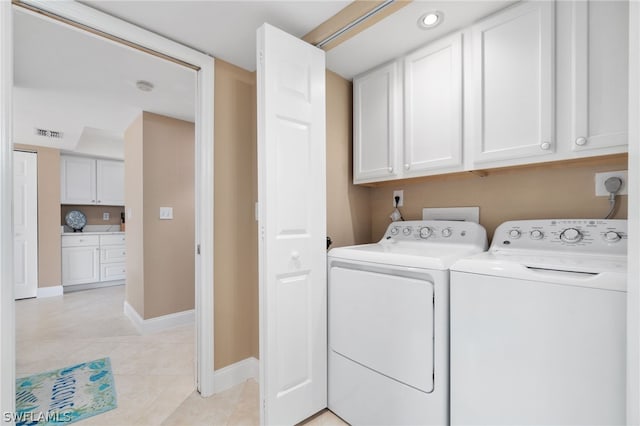 clothes washing area with separate washer and dryer, cabinets, and light tile patterned floors