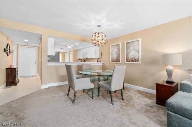 dining space featuring a chandelier, light carpet, and baseboards