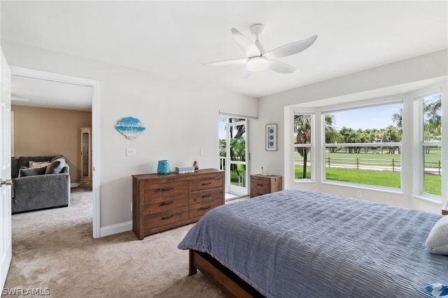 bedroom with light carpet, access to outside, multiple windows, and baseboards