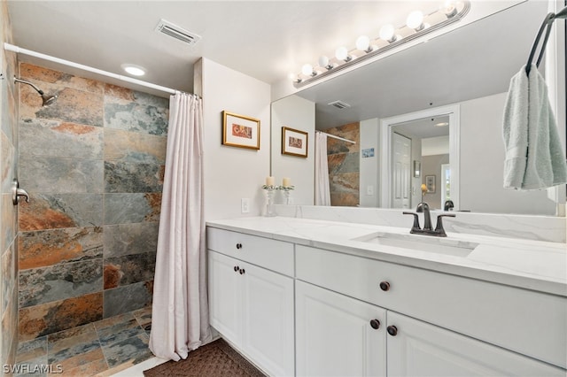 bathroom with stone finish flooring, visible vents, vanity, and a shower stall