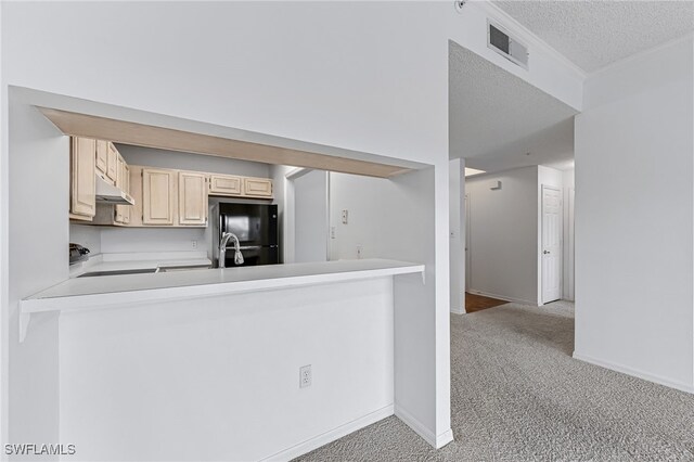 kitchen featuring under cabinet range hood, light carpet, visible vents, light countertops, and freestanding refrigerator