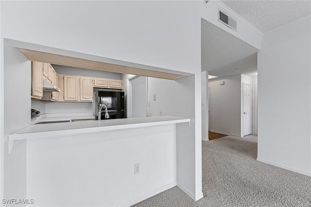 kitchen featuring visible vents, under cabinet range hood, freestanding refrigerator, carpet flooring, and stove