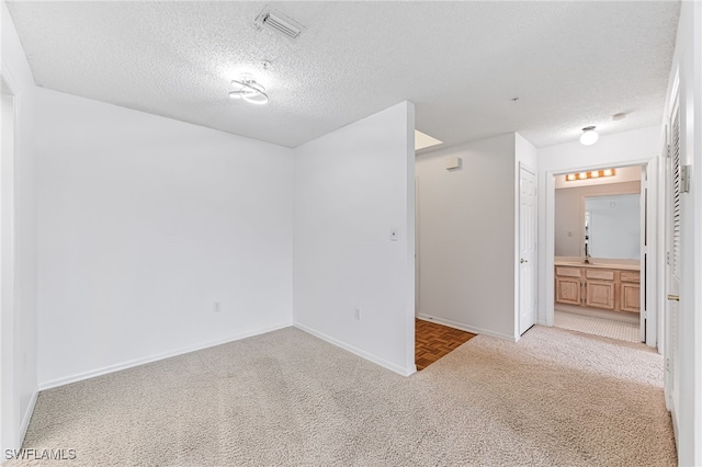 unfurnished room featuring light carpet, a textured ceiling, visible vents, and baseboards