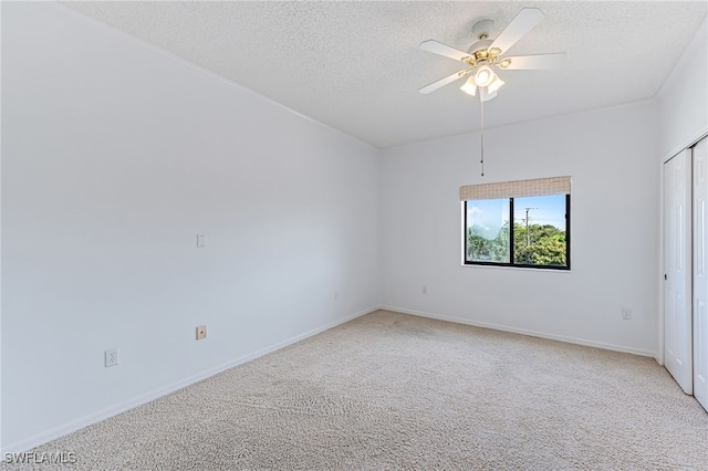 spare room featuring a ceiling fan, light colored carpet, a textured ceiling, and baseboards