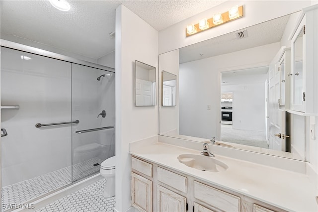 full bath with visible vents, toilet, a shower stall, a textured ceiling, and vanity