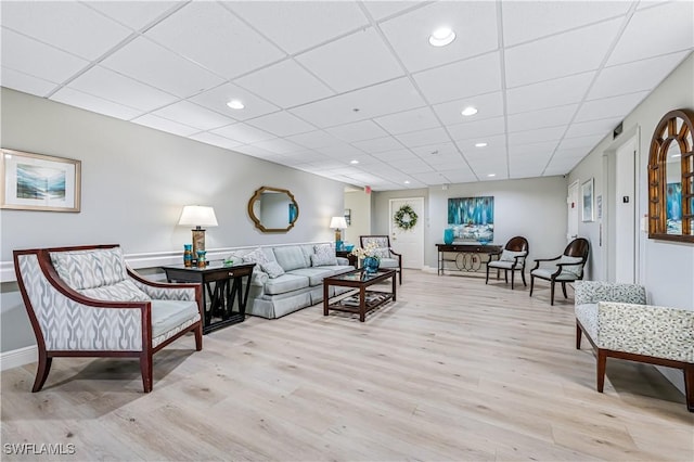 living room with recessed lighting, light wood-type flooring, and a drop ceiling