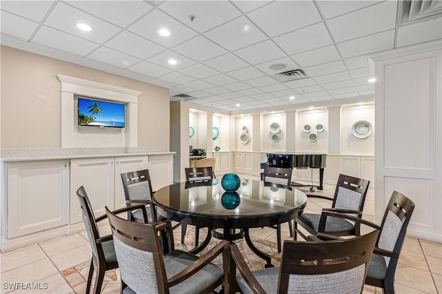 dining room with light tile patterned flooring, a decorative wall, and visible vents