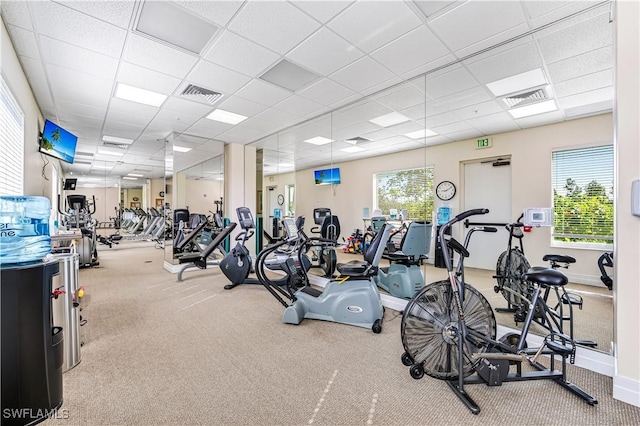 exercise room with a paneled ceiling, carpet floors, baseboards, and visible vents