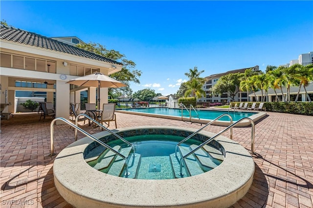 community pool with a patio area and a hot tub