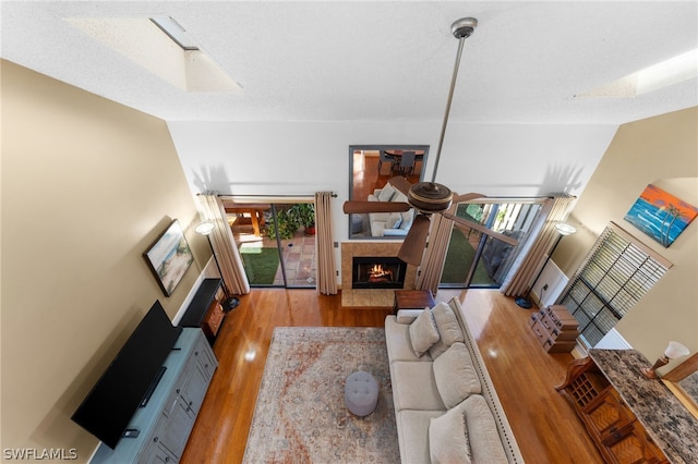 living room featuring lofted ceiling, a healthy amount of sunlight, light hardwood / wood-style flooring, and a high end fireplace