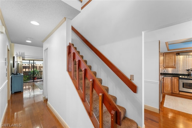 stairs with hardwood / wood-style floors and a textured ceiling