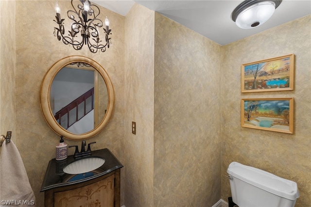 bathroom with vanity, toilet, and a notable chandelier