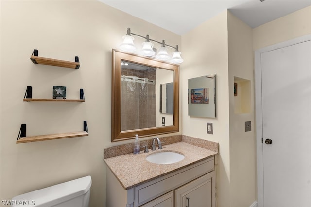 bathroom featuring toilet, vanity, and tiled shower