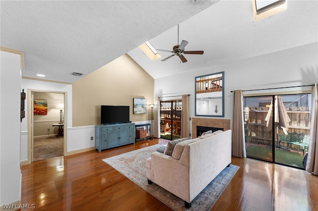 living room with a textured ceiling, wood-type flooring, a skylight, ceiling fan, and high vaulted ceiling