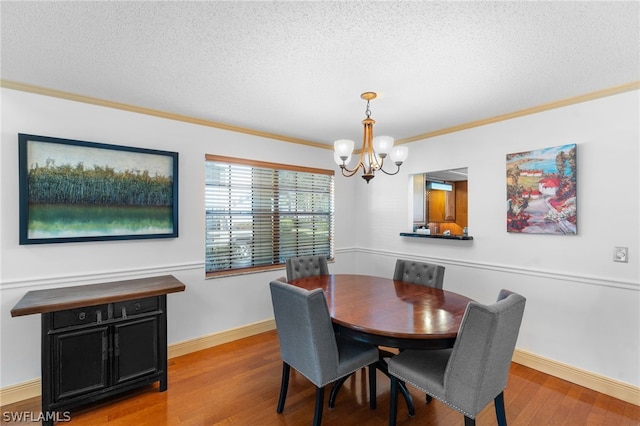 dining area featuring crown molding, hardwood / wood-style floors, an inviting chandelier, and a textured ceiling