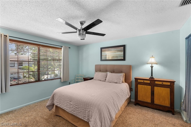 bedroom with ceiling fan, light colored carpet, and a textured ceiling