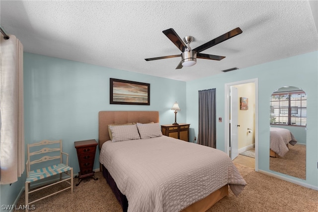 carpeted bedroom with ceiling fan, connected bathroom, and a textured ceiling