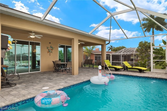 view of swimming pool featuring a patio area, ceiling fan, and glass enclosure