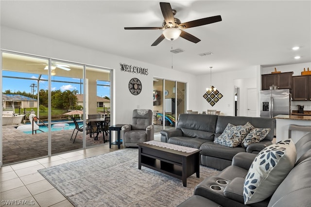 tiled living room featuring ceiling fan with notable chandelier