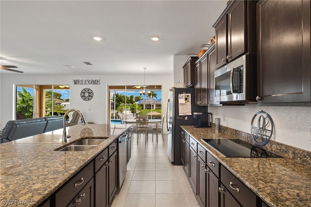 kitchen featuring light tile patterned floors, ceiling fan with notable chandelier, stainless steel appliances, dark brown cabinetry, and sink