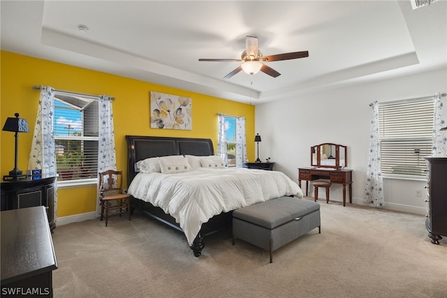 carpeted bedroom with ceiling fan and a tray ceiling