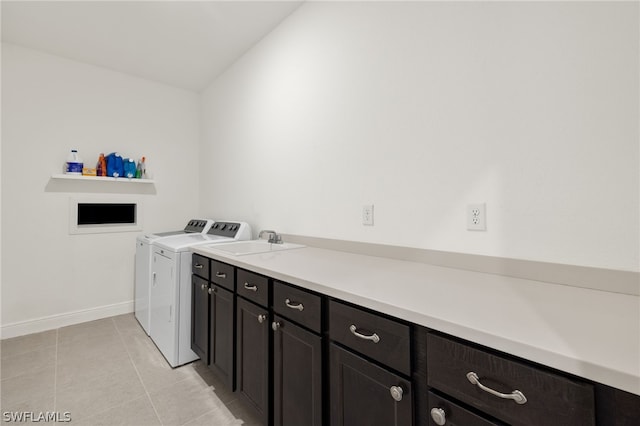 clothes washing area featuring light tile patterned floors, sink, washer and clothes dryer, and cabinets